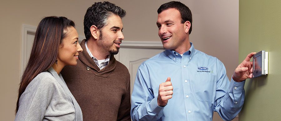 HVAC technician talking to a couple about their wifi thermostat